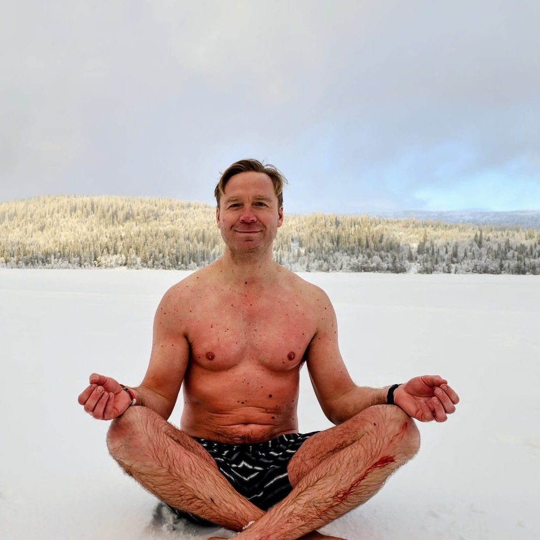 Morten Barkfeld sitting cross-legged in shorts on a frozen lake in winter